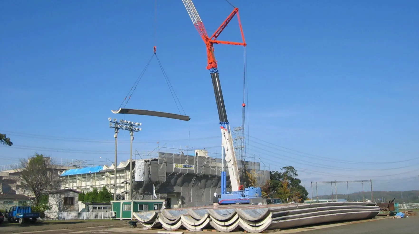 大型クレーンが建設現場でコンクリート製の構造物を吊り上げている様子。