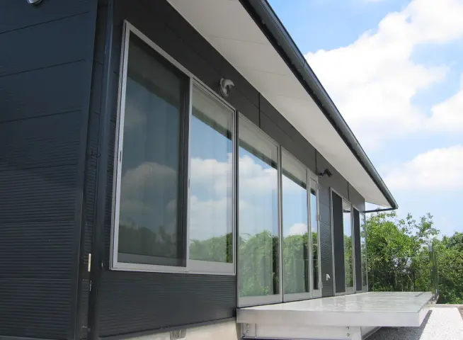 モダンな住宅の外観で、大きなガラス窓が並び、自然光を取り込む設計が特徴的